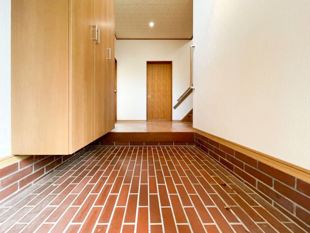 ウッド調の建具が魅力的な温かみのある玄関。吹き抜けの窓からは心地の良い光が入り、葉っぱの影がゆらゆらと時間の流れをゆったりと感じられる空間です。