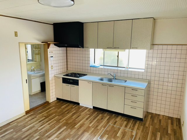 壁付けタイプで空間を広く使えるキッチンは、作業効率の良いシンプルな動線が魅力。窓から自然光が入り、明るく開放的な空間で日々のお料理も快適です。収納も豊富に確保されており、調理器具や食器もすっきり整理。