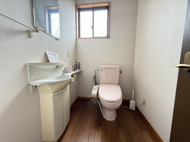 小窓からの自然光が心地よく差し込む、明るく清潔感のあるトイレです。手洗いカウンターも設置されており、動線がスムーズで衛生的です。落ち着いた色合いの内装が、リラックスできる空間を演出してくれます。