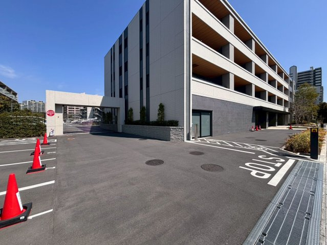 敷地南西側に面した駐車場出入口。シャッター外に来客用駐車場有り（8：00～20：00は100　円/1時間。20:00～翌8:00は1、000円/1回）。
