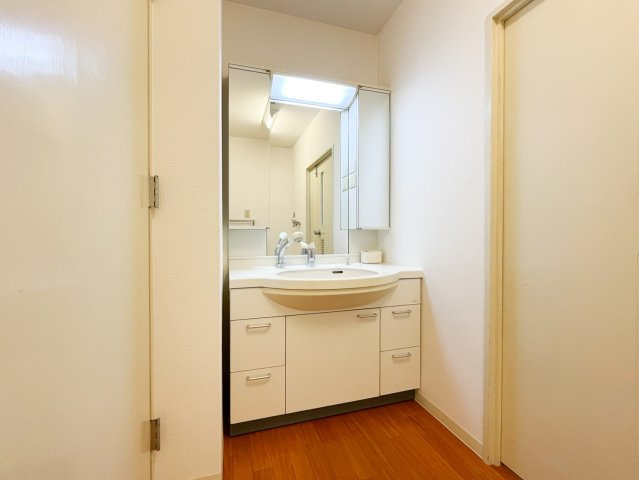 洗面台は収納が充実しており、広々とお使いいただけるサイズです。三面鏡とシャワー付き水栓は朝の忙しい時間に嬉しいですね。