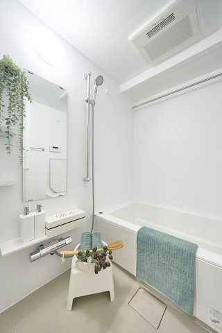 ホワイト基調の清潔感あふれる空間に縦長鏡を備えたバスルーム。使い勝手の良いシャワーや壁面棚が設置されており、一日の疲れをゆったりと癒やせる機能的な浴室空間となっています。