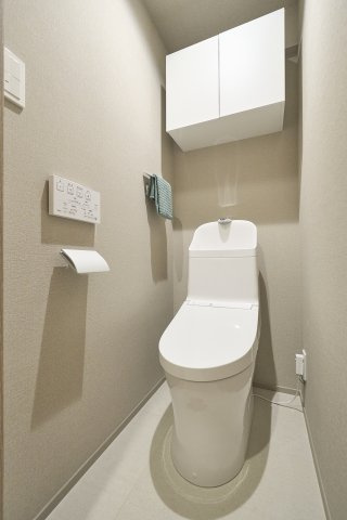 上部に扉付きの収納棚を備えた、すっきりと片付くトイレ空間。トイレットペーパーなどを目隠しして整理でき、温水洗浄便座を完備した衛生的で快適な設備仕様となっています。