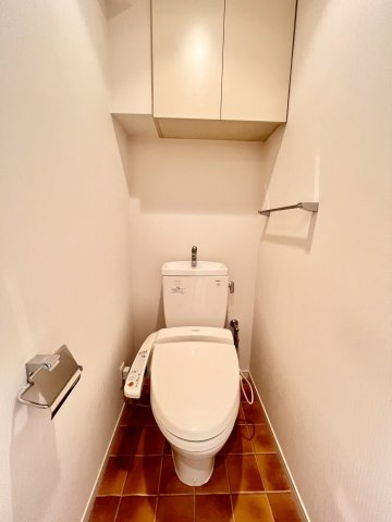 ウォシュレット付きの快適なトイレ。上部にトイレットペーパーや掃除用具を収納できる便利な棚付きです。