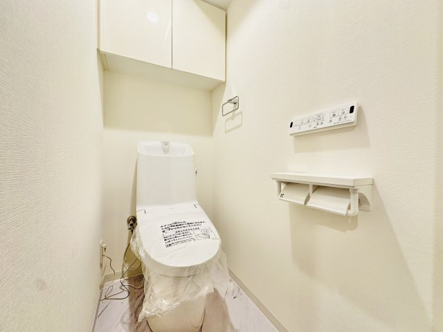 トイレも便器ごと新規交換済。　温水洗浄便座付きで年中快適にご使用いただけます。　上部にはトイレットペーパーなどのストック品を綺麗に収納できる吊り戸棚を備え、足元をすっきりと清潔に保つことができる空間。