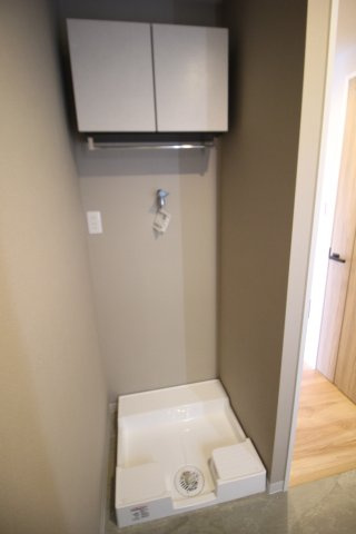 洗濯機置き場は壁内に収まり、行き来の邪魔になりません。上部の吊戸棚も便利です