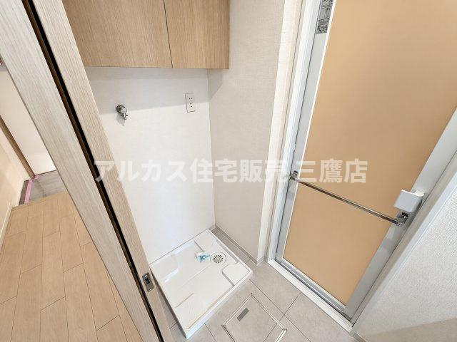 洗面室内に設けられた洗濯機置き場です。上部には収納戸棚が設置されており、洗剤やタオル類をすっきりと整理できます。