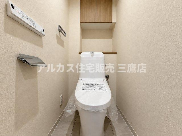 すっきりとしたフォルムの温水洗浄便座付きトイレです。壁面にはペーパーホルダーや操作パネルが機能的に配置されています。