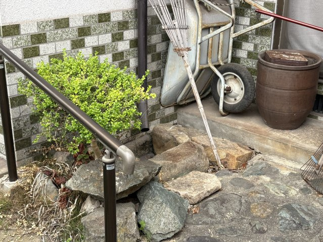 外部アプローチには手すりが設置されており、ご高齢の方や小さなお子様にも安心して利用できる設計。庭石や植栽が自然の温もりを感じさせ、落ち着いた雰囲気を演出しています。玄関へと続く動線も安全に確保。