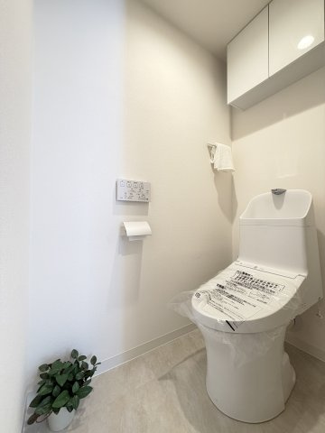 【トイレ】　吊戸棚付きで、白を基調とした清潔感のある空間です。トイレは温水洗浄便座付です。