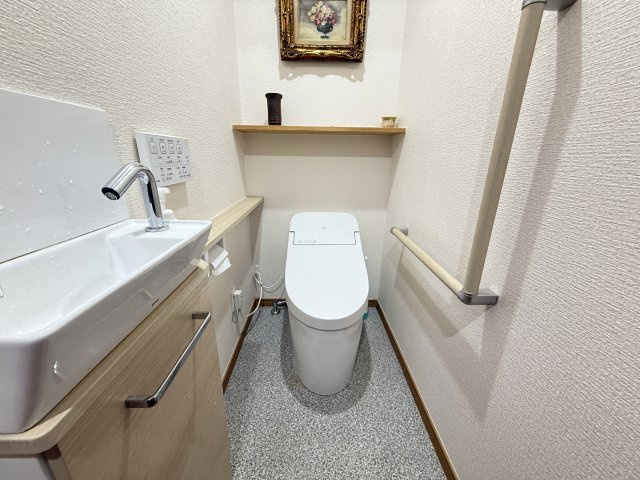 手すり付きで安心して使用できるトイレ空間です。手洗いカウンターと収納棚が設けられており、実用性にも配慮されています。清潔感のある内装で、毎日気持ちよく使える落ち着いた雰囲気が魅力です。