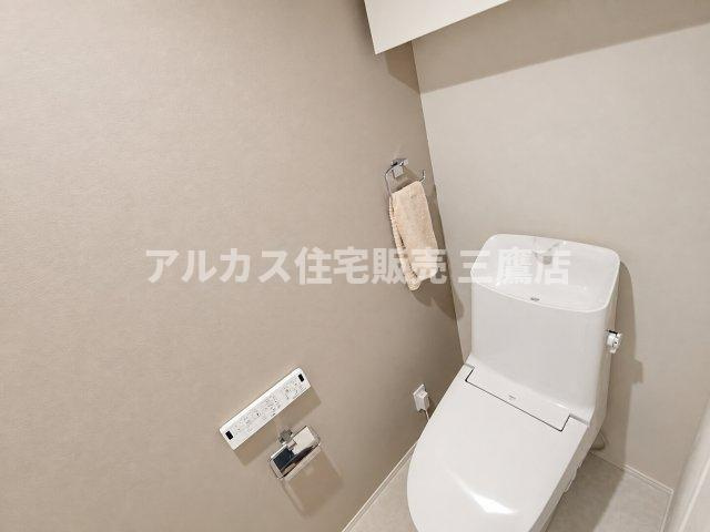 温水洗浄便座や手洗い洗面、ペーパーホルダーを備えた清潔感溢れるトイレ空間。落ち着いた色調のクロスで居心地の良い雰囲気を演出しています。　