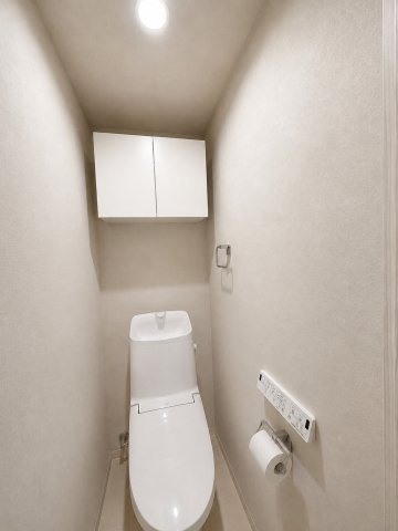 上部に扉付きの収納棚を備えた、すっきりと片付くトイレ空間。トイレットペーパーや掃除用具を目隠しして整理でき、温水洗浄便座を完備した衛生的で快適な設備仕様となっています。