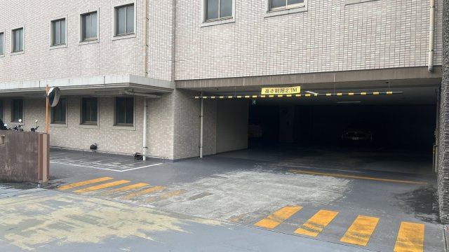 建物内へ直接つながる屋内駐車場の入口です。高さ制限は2.1mとなっており、入口部分もゆとりのある設計。屋根付きのため、雨天時にも雨の影響を受けにくく、日常の車の出し入れがしやすい駐車環境です。　