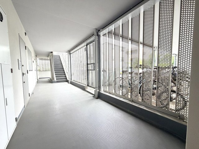 光と風を通しながらプライバシーを守る、外観と一体となったパンチングパネル。雨に濡れない屋根付き廊下で駐輪場へも繋がる、デザインと利便性を兼ね備えたアプローチ。