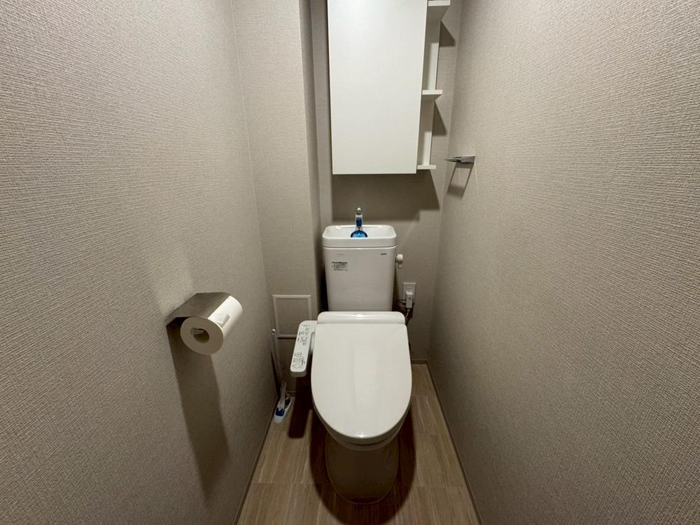 【トイレ】　手洗い器一体型のトイレは、温水洗浄便座付きです。吊戸棚があり、トイレットペーパーや掃除用具などのストックが可能です。