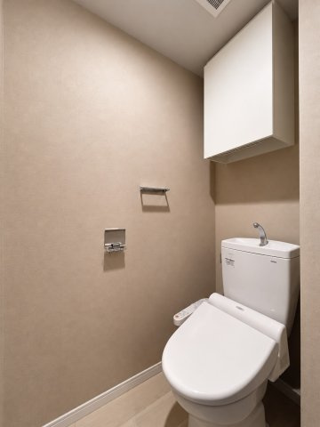 温水洗浄便座付きのトイレ！上部の吊戸棚にはトイレットペーパーなどのストックも収納できます。※画像加工により家具等を消去しています