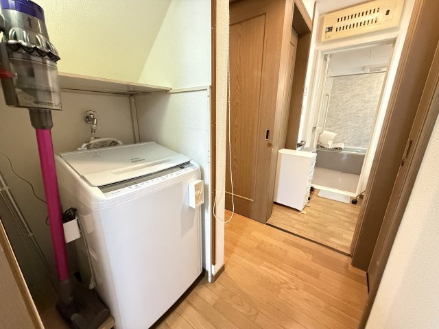 洗濯機置場は洗面室近くに配置されています。上部には棚を設置できるスペースもあり、洗剤やタオル類の収納場所として活用可能です。廊下部分にもゆとりがあり、毎日の家事を快適に行いやすい空間となっています。