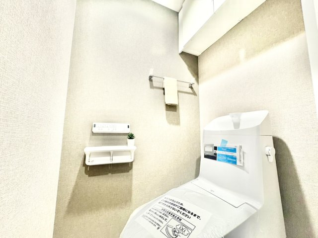 上部にトイレットペーパーや掃除用品をスマートに隠せる扉付き吊り戸棚を完備。壁掛けリモコンや便利な2連ペーパーホルダーを採用し、足元をいつでも広くすっきりと美しく保てる安心のトイレ空間です。