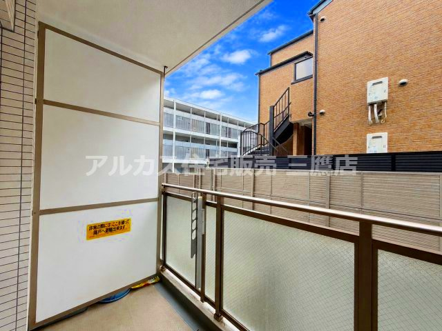 バルコニーの別角度。非常時の避難ハッチ・隔て板が設置されており、外部からの視線を遮るフェンスも備わっています。
