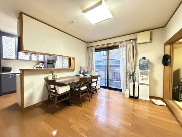 木目の美しいフローリングが温かみを感じさせるダイニングスペース。南向きの掃き出し窓からたっぷりと陽光が入り明るく開放的な雰囲気です。キッチンとの距離も近く、家族の会話が自然と弾む居心地の良い空間です。