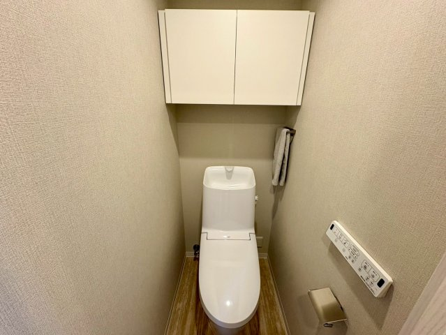 白を基調とした清潔感あふれるトイレ空間。上部には便利な吊戸棚があり、掃除用品などの収納に便利です。