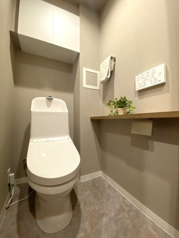 トイレ新規交換　玄関近くの廊下に配置された独立トイレ。新規交換済みの快適な仕様で、上部にはペーパーなどのストックに便利な収納棚も備わっています。