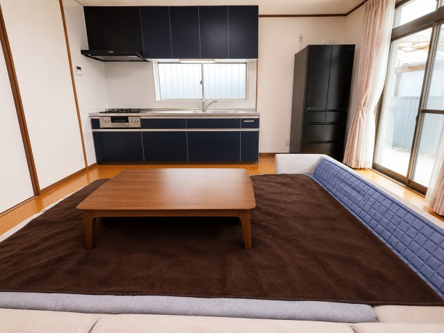大きな掃き出し窓から自然光が差し込む明るいリビング空間です。落ち着いた色合いのフローリングとネイビーカラーのキッチンが調和しスタイリッシュな印象を演出。和室と隣接しておりくつろげる開放感のある空間です