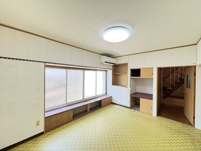 大きな窓からやわらかな自然光が差し込む明るいLDKです。窓際にはカウンター収納が設けられており、飾り棚や収納スペースとして活用できます。エアコンも設置されているため、季節を問わず快適に過ごせる空間。