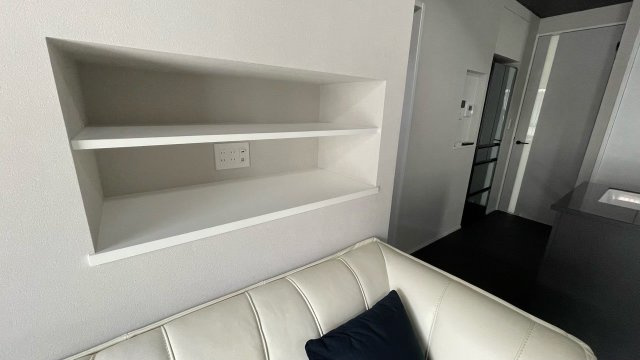 リビングの壁面には、奥行きを抑えた造作棚を設け雑誌や小物をすっきり収納。コンセント付きで、スマートフォンの充電やインテリア照明の設置にも便利。壁面に溶け込むデザインで圧迫感がなく実用的な収納スペース。