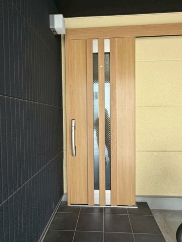 中央に二本の採光ラインが並ぶ玄関ドア。シックな外壁と明るい木目の組み合わせがおしゃれです。