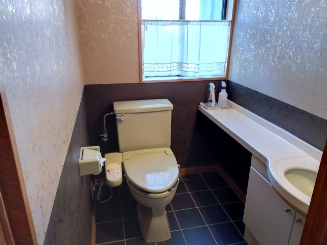 居住スペースのトイレです。ブラウンと白のクロスで高級感のある室内です。手洗い場も併設しているので衛生的です。収納もあるのでトイレットペーパーのストックも置けます。