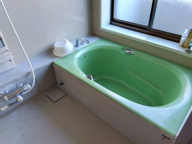 窓があるので明るい室内です。緑の可愛らしい浴槽です。備え付けの台があるのでシャンプーを置けて便利です。