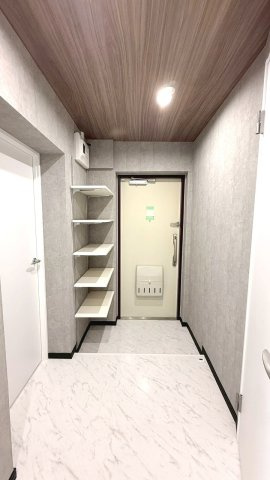白の大理石調フロアが輝く、高級感あふれる玄関。シューズ棚完備で、明るく清潔な空間が家族を迎え入れます