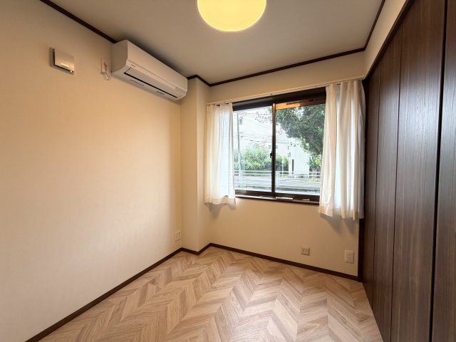 足元のヘリンボーン調フロアとダークブラウンの建具が上質なアクセントになったお部屋。窓からは爽やかな自然光と緑が覗き、毎日の暮らしを心地よく彩るプライベート空間です。