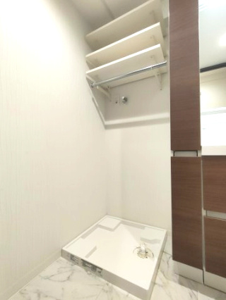 【室内洗濯機置き場】　棚板の高さを自由に動かせる可動棚を採用したニッチスペースに、ランドリーグッズやリネン類を収納しておけます。