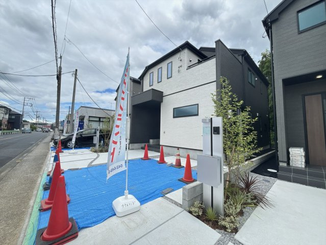 右側から見た外観写真です。こちらの角度からも建物の立体感をご確認いただけます。手前には広い駐車スペースを確保しております。青空に映える明るい外観で、毎日を気持ちよく過ごせそうです。