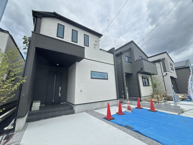 左側から見た外観写真です。建物の立体感や窓の配置を確認いただけます。手前には広い駐車スペースがあり、車を2台停めてもまだ余裕のある広さです。青空の下で明るい印象の住まいです！