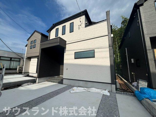 完成した建物の外観写真です。明るい白い外壁が青空に映える、モダンで清潔感のあるデザインです。手前にはコンクリート舗装された駐車スペースがあり、日々の車の出し入れもスムーズに行えます！