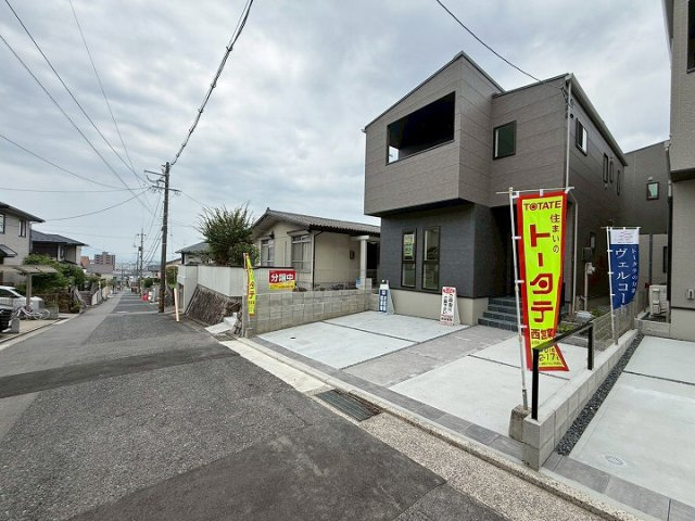 グレーの濃淡を活かしたモダンな外観デザインの一戸建てです。2F部分のインナーバルコニーが外観のアクセントになっています。前面道路や隣地との間隔が確保されており、室内の採光や通風にも配慮された配置です。