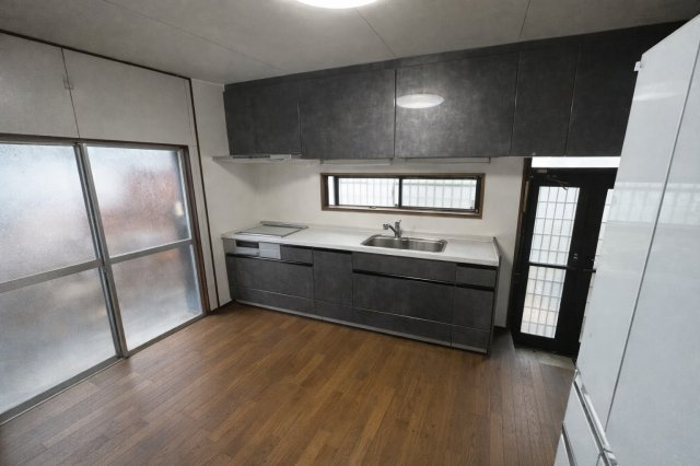 ダークトーンで統一されたシステムキッチンが空間を引き締めるダイニングキッチン。作業スペースも広く、調理や配膳もスムーズに行えます。横長の窓から採光も確保され、明るさと使い勝手を兼ね備えた空間です。