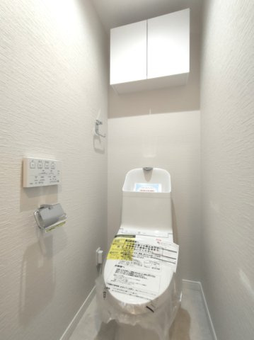 【トイレ】　温水洗浄便座・壁付けリモコン付き。吊り戸棚を備えた機能的なトイレです。