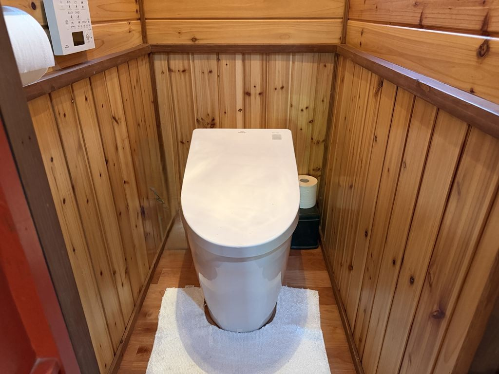 木の温もりあふれる板張りの壁面に、高機能な温水洗浄便座を備えた、清潔感と心地よさを兼ね備えた快適なトイレ空間です。