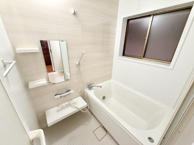 明るい色合いで清潔感のあるバスルーム。ゆったりと浸かれる浴槽で一日の疲れを癒せます。サーモ水栓付きで温度調整も簡単。窓があるため自然換気ができ、カビ対策にも効果的です。手すりも設置。安心して入浴可能。