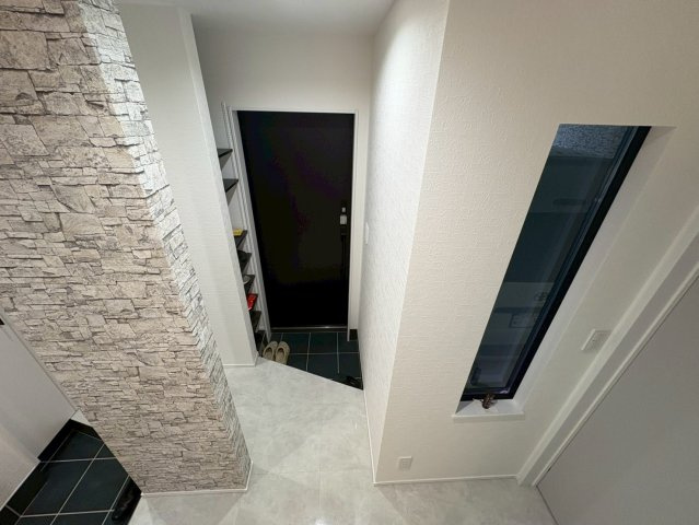 採光を確保したスリムな窓とシックなブラックドアが印象的な勝手口。石調のクロスやタイル床が高級感を演出し統一感のあるデザイン。室内からも出入りしやすくゴミ出しや荷物の搬入など配慮された実用的な空間。