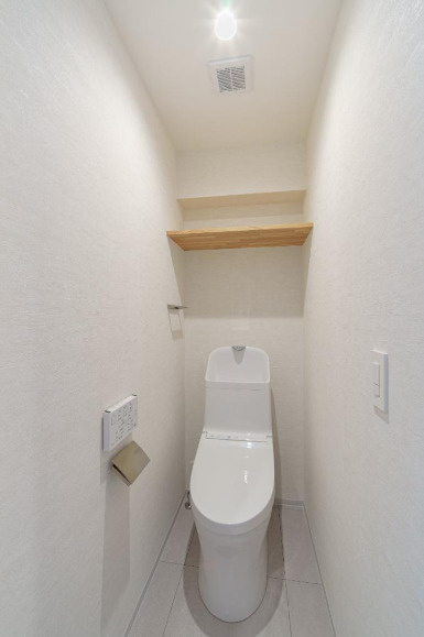 トイレットペーパーのストックや掃除用具を生活感を出さずに収納できる、便利な上部吊戸棚付き。限られたスペースを最大限に広く、美しく使うための嬉しい工夫が施されたクリーンな空間です。