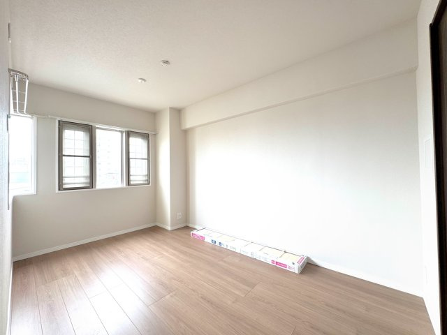 【洋室約6帖】主寝室に最適なゆとりある洋室。角部屋ならではの二面採光で、朝日を浴びて気持ちよく目覚めることができます。大きめのベッドを置いてもくつろげる、落ち着いた空間です。