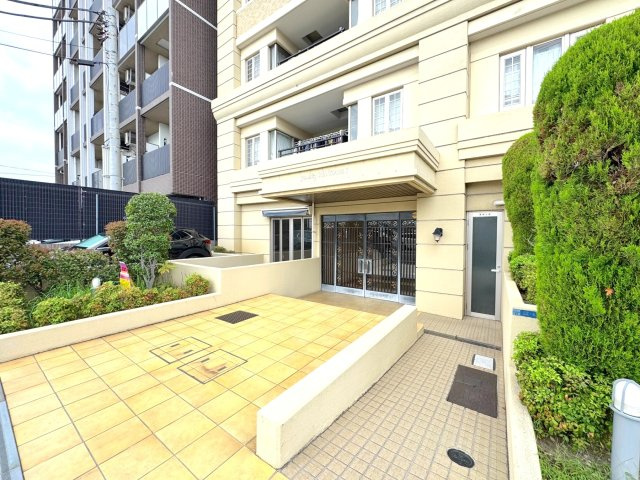 【重厚感のあるマンション外観】タイル貼りで落ち着いた雰囲気のエントランスアプローチ。手入れが行き届いた植栽が、住まう方や来客を優しく迎え入れてくれます。