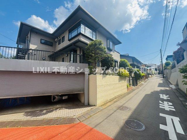 角地ならではの開放感が魅力の住まい。植栽が整えられた落ち着きある外観に、シャッター付きガレージも備えています。前面道路は住宅街らしい穏やかな雰囲気です。