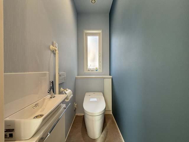 落ち着いた色合いでまとめられたトイレ空間は、清潔感と快適性を兼ね備えています。手洗い器付きで使い勝手も良く、窓からの自然光により明るさも確保。シンプルながら機能的で、日常使いに配慮された空間設計。